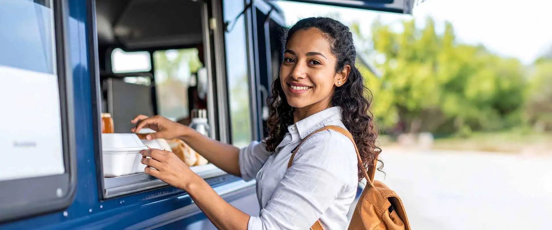 Student smiling while receiving box of food from food truck